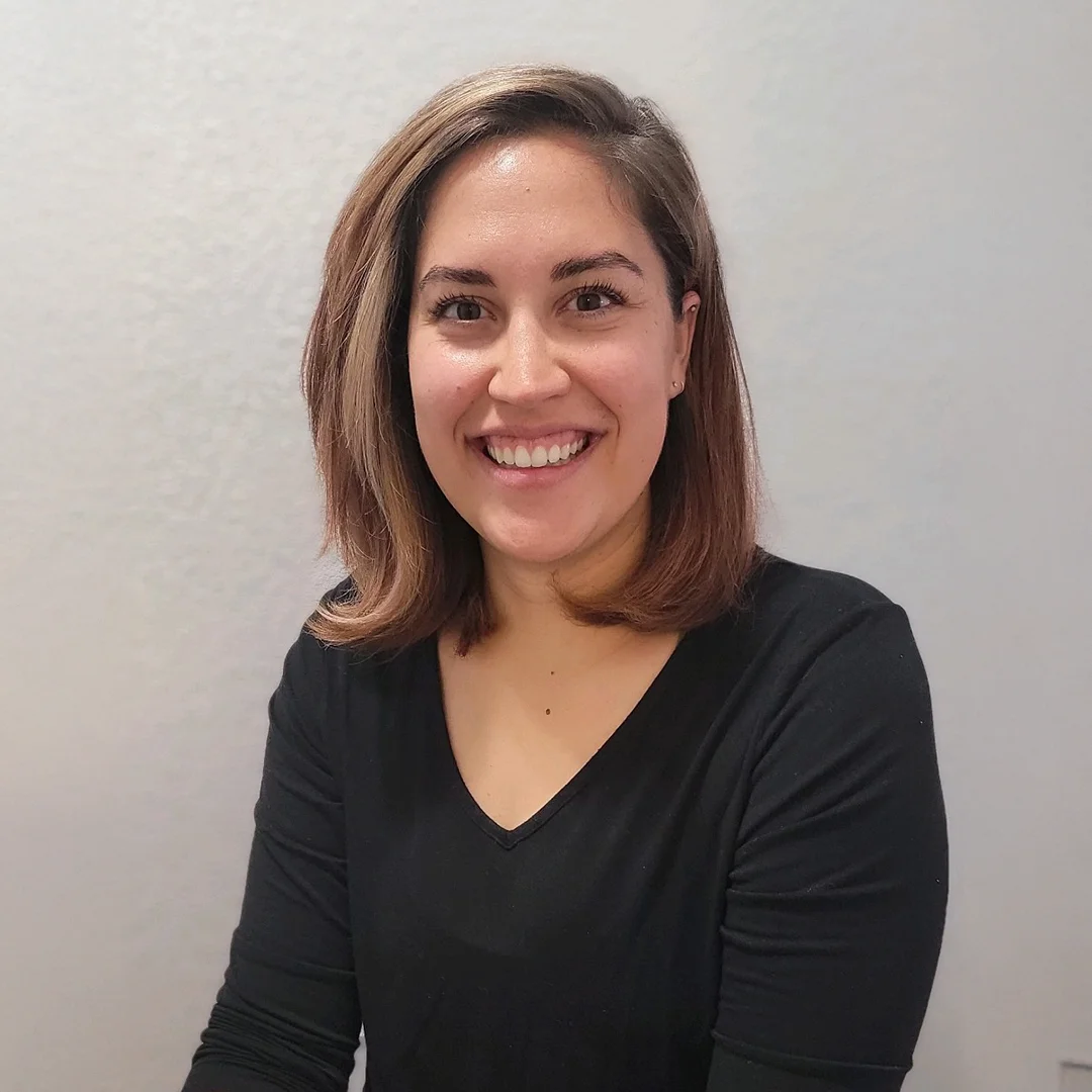 Brittany Zufelt smiling in front of a light background, wearing a black long-sleeve top.