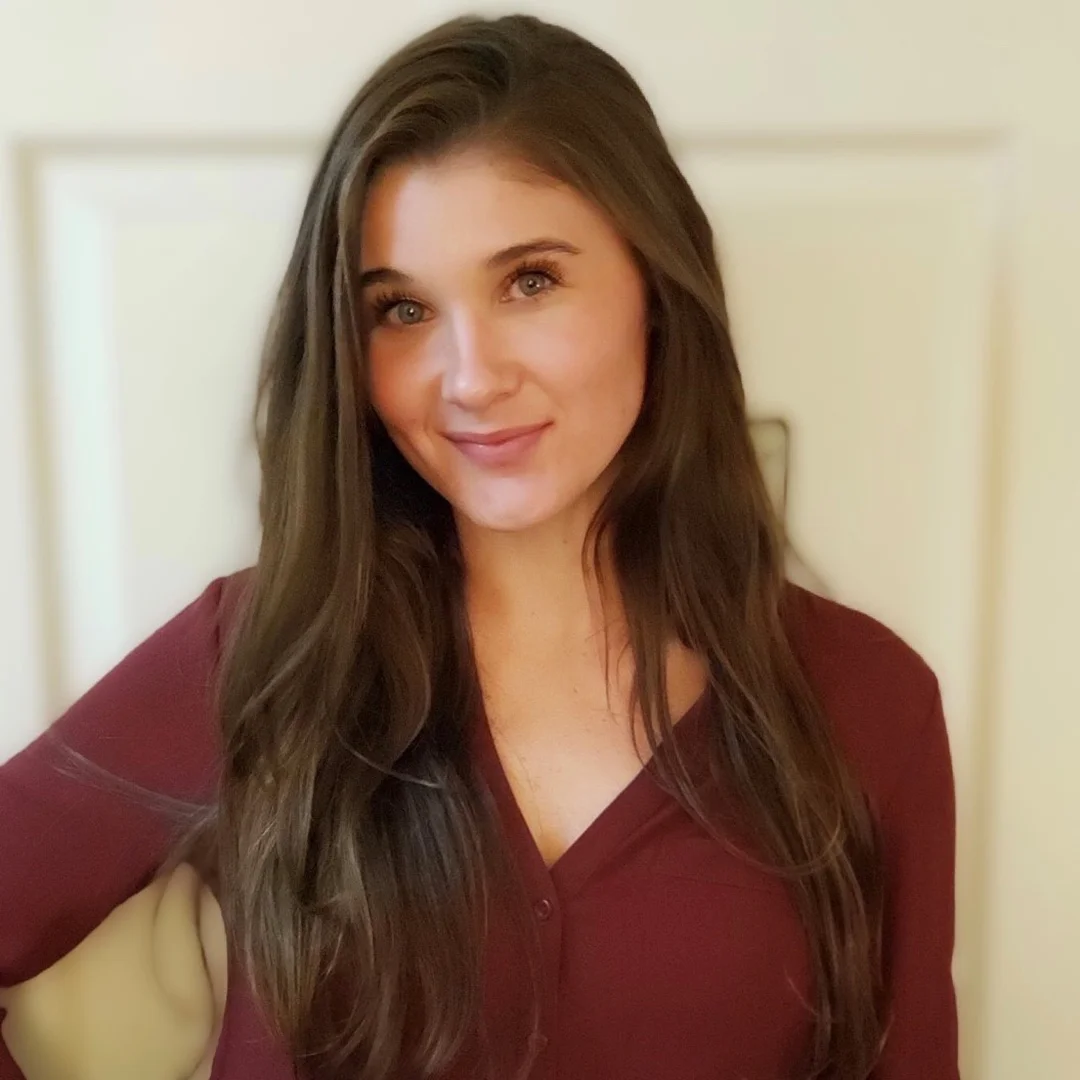 Professional headshot of Sadie Horwath smiling indoors, wearing a burgundy blouse with long brown hair.